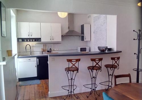eine Küche mit weißen Schränken und Barhockern in der Unterkunft Les Appartements du 31 - Centre Ville - 1er étage - 56 m2 in Quimper