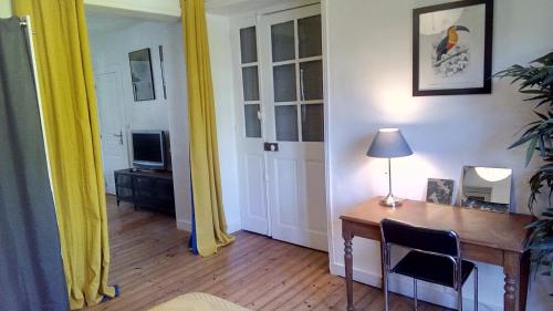 Zimmer mit einem Schreibtisch mit einer Lampe und einem TV in der Unterkunft Les Appartements du 31 - Centre Ville - 1er étage - 56 m2 in Quimper