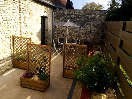 eine Terrasse mit einem Tisch und einem Regenschirm und einigen Pflanzen in der Unterkunft Un Figuier dans notre Jardin in Beaune-la-Rolande