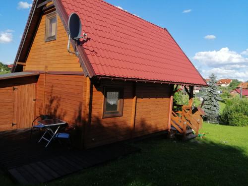 a house with a red roof and a chair on the porch at PILGRIM domek gościnny w Gietrzwałdzie na Warmii in Gietrzwałd