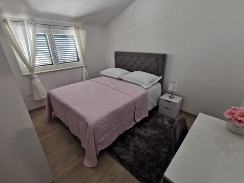 een slaapkamer met een roze bed en een raam bij Apartmani "Allegro" in Podaca