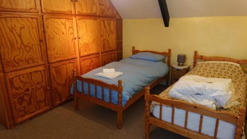 a bedroom with two twin beds and wooden cabinets at Moonfleat in West Quantoxhead