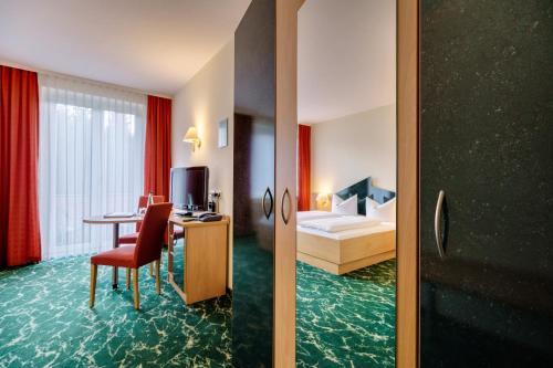 a hotel room with a bed and a desk and a room at Waldhotel Vogtland in Klingenthal
