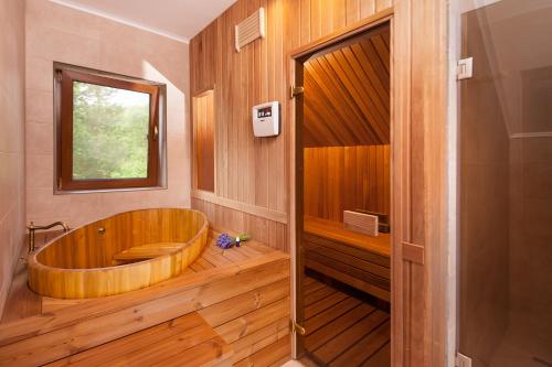 a wooden tub in a bathroom with a window at Rose Hip Hill Guesthouse in Valea Tîrnei