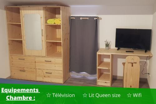 Cette chambre comprend un bureau, une télévision et une armoire en bois. dans l'établissement ~☆ T2 Les Pins du Midi - AGDEBNB ☆~, à Agde