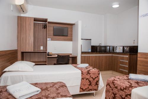 a hotel room with two beds and a kitchen at Hotel Belugi in Goiânia