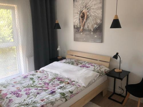 sypialnia z łóżkiem z kwiatową narzutą i oknem w obiekcie Apartament Avanti z klimatyzacją i garażem w Toruniu