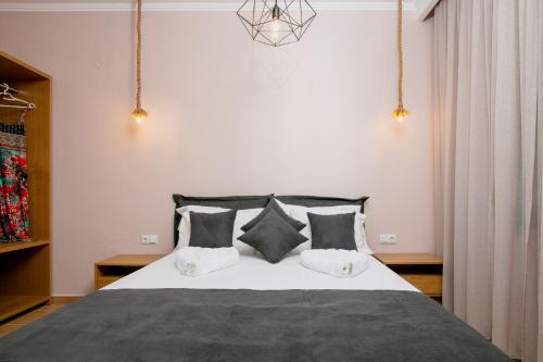 1 dormitorio con 1 cama con almohadas blancas y negras en Arion Apartments en Skála Potamiás