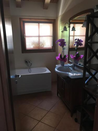 bagno con vasca, lavandino e specchio di Casa del Balcone Fiorito a Cormòns