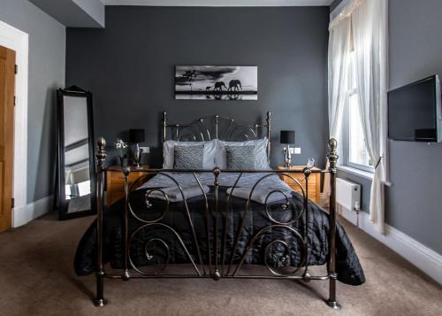 a bedroom with a black bed and a television at Scotia House - Beautifully Presented Accommodation in Harrogate