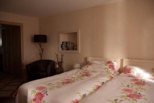 1 Schlafzimmer mit einem Bett mit Blumenbettwäsche und einem Stuhl in der Unterkunft Entredigue in Divonne-les-Bains