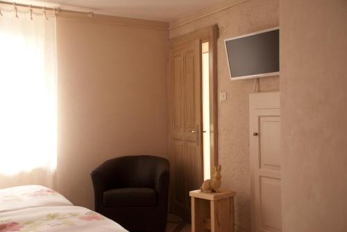 1 dormitorio con silla y TV en la pared en Entredigue, en Divonne-les-Bains