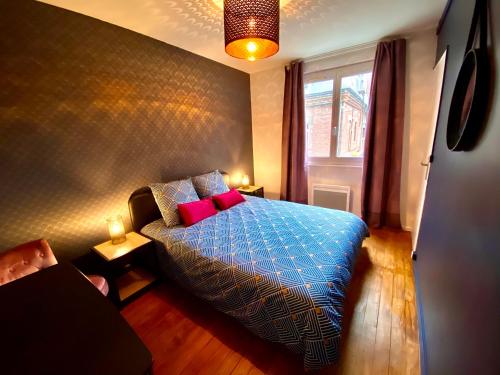 a bedroom with a blue bed with red pillows and a window at 6- Appartement de 2 pièces refait à neuf en centre ville in Dieppe