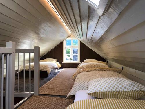 un dormitorio en el ático con 4 camas y una ventana en Den Gule Krambua - Gamle Lærdalsøyri - main street old town en Lærdalsøyri
