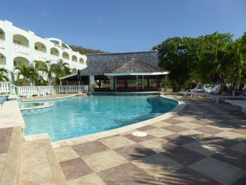 a large swimming pool in front of a building at Kalinago Beach Resort in Saint Georgeʼs