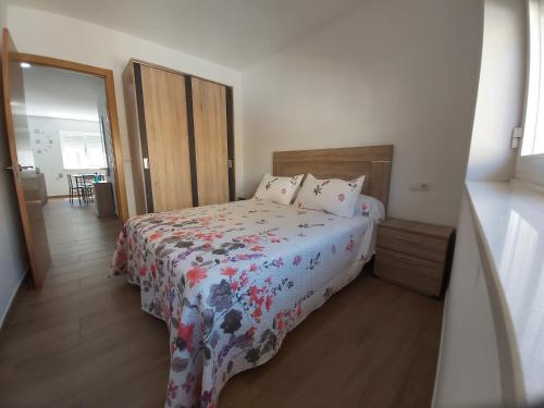 1 Schlafzimmer mit einem Bett mit Blumenbettdecke in der Unterkunft Apartamento Adriana in O Pindo