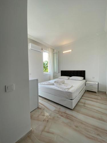 a white bedroom with a bed and a window at Kiriş Garden Hotel in Kemer