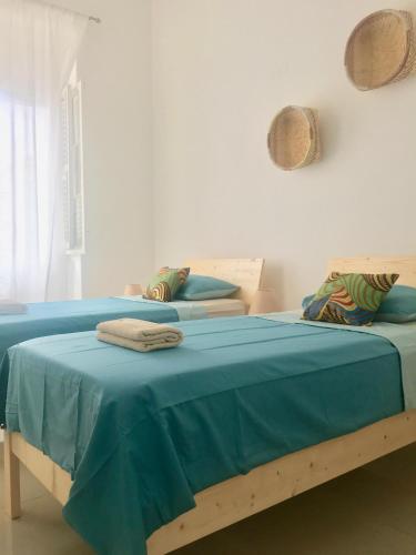 two beds with blue sheets in a white room at Casa Sodadi in Praia