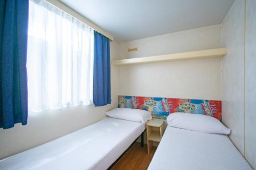 zwei Betten in einem kleinen Zimmer mit Fenster in der Unterkunft Camping Parco Vacanza Partaccia 2 in Marina di Massa