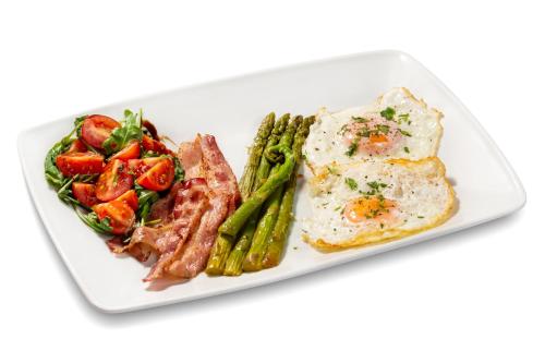 a plate of food with eggs and bacon and vegetables at Hotel Am Ring in Sibiu