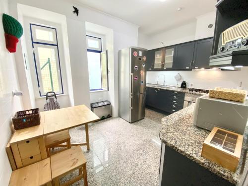 a kitchen with black cabinets and a stainless steel refrigerator at Luxury Vintage apartment by MyPlaceForYou, at the city centre next to Marquês de Pombal in Lisbon