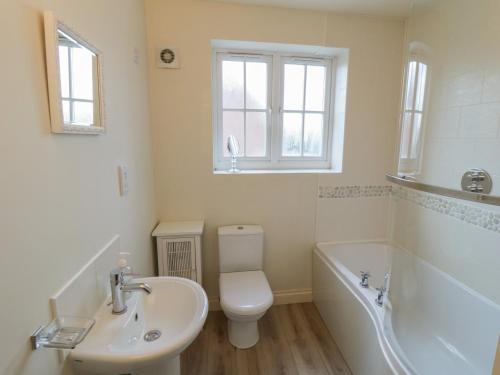 a bathroom with a toilet and a sink and a tub at Driftwood in Filey