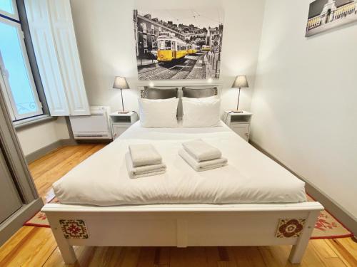 Cama blanca en habitación con tren amarillo en Luxury Vintage apartment by MyPlaceForYou, at the city centre next to Marquês de Pombal, en Lisboa