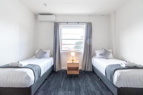 two beds in a room with a window at Sydney Junction Hotel in Hamilton