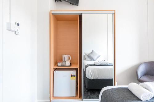 a room with a mirror and a bed and a refrigerator at Sydney Junction Hotel in Hamilton
