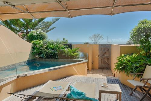 an outdoor patio with a swimming pool and an umbrella at Beach Suites in Byron Bay