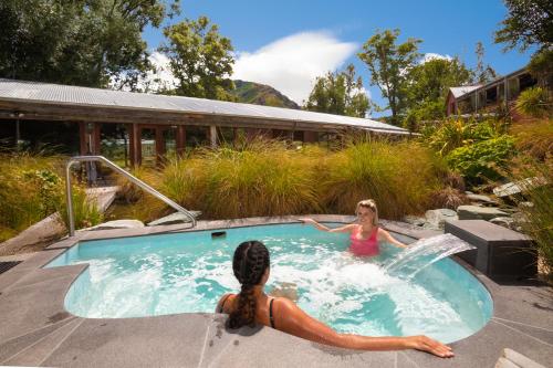 dos chicas en un jacuzzi en un patio trasero en Millbrook Resort, en Arrowtown