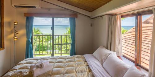 a bedroom with a bed and a view of the ocean at Ishigaki Sunset Cove in Ishigaki Island