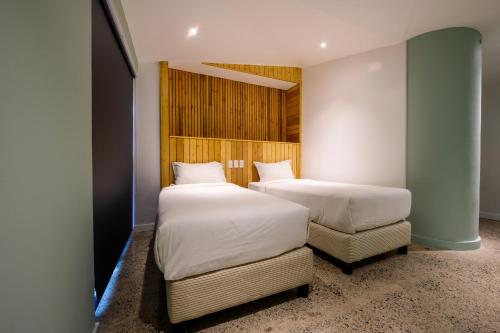 a bedroom with two beds and a chair in it at G1 Lodge in Baguio