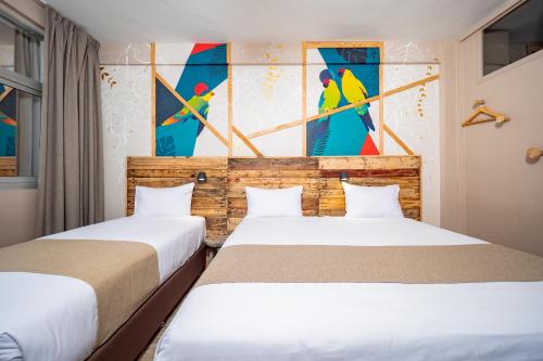 two beds in a room with paintings on the wall at Gondwana City Art in Noumea