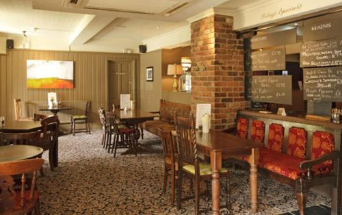 a dining room with tables and chairs and a table and chairsktop at Raven Hotel by Greene King Inns in Hook