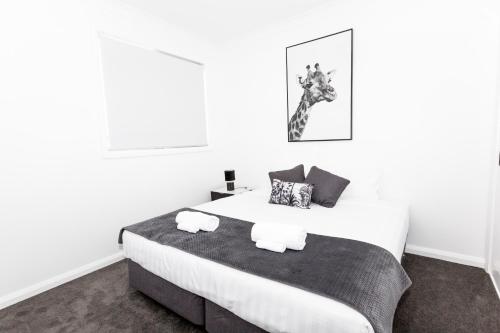 TWO TEN Sleeps 10! Luxury CBD Accommodation في واجا واجا: غرفة نوم عليها سرير وفوط