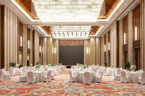 a ballroom with white tables and chairs and a projection screen at Pullman Changbaishan Resort in Fusong