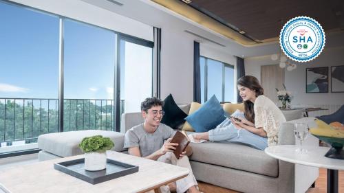 a man and woman sitting on a couch in a living room at Amanta Hotel & Residence Sathorn in Bangkok