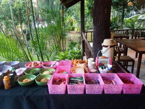 a table topped with pink containers filled with food at Baan Pak Rim Kuaen Resort in Ratchaprapha