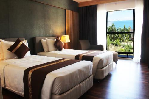 two beds in a hotel room with a large window at Batam View Beach Resort in Nongsa