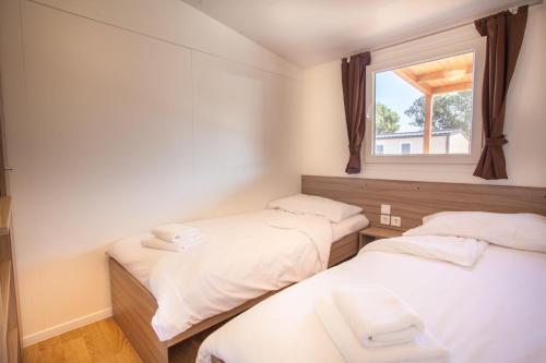 two beds in a room with a window at Mobile Homes Delta Marine at Campsite Rapoća in Nerezine