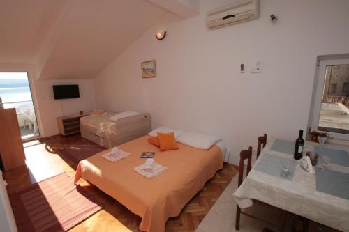 a bedroom with a bed and a table and a window at Apartmani Damir Livajić in Omiš
