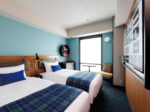 a hotel room with two beds and a flat screen tv at DEL style Osaka Shin Umeda by Daiwa Roynet Hotel in Osaka