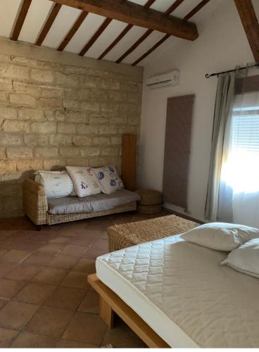 une chambre avec un lit et un mur en pierre dans l'établissement Les Olivades, à Vauvert
