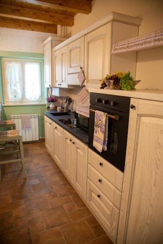 a kitchen with white cabinets and a black stove top oven at La Beppa - Casa Vacanza in Pontremoli