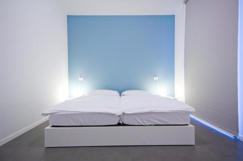 uma cama branca num quarto com uma luz azul em Mecki Apartments em Nago-Torbole