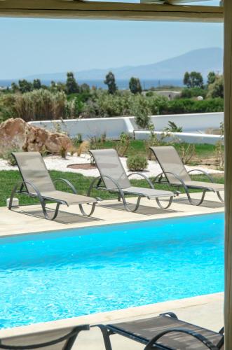 two chairs sitting next to a swimming pool at Sea & Olives Suites Hotel and Villas in Plaka