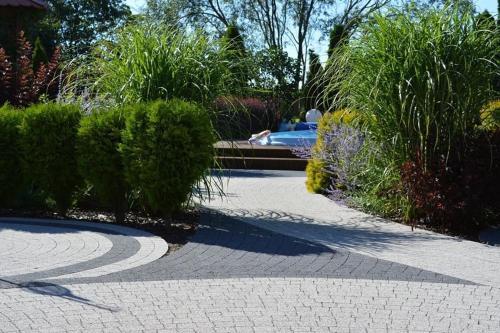 een geplaveide loopbrug in een tuin met struiken bij Pokoje Gościnne Zielony Dom in Frombork