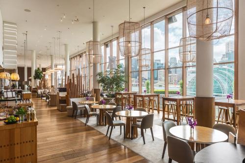 un restaurante con mesas, sillas y ventanas grandes en Novotel Sydney Darling Harbour en Sídney