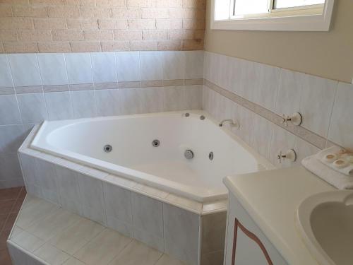 a white bath tub in a bathroom with a sink at Blayney Central Motel in Blayney